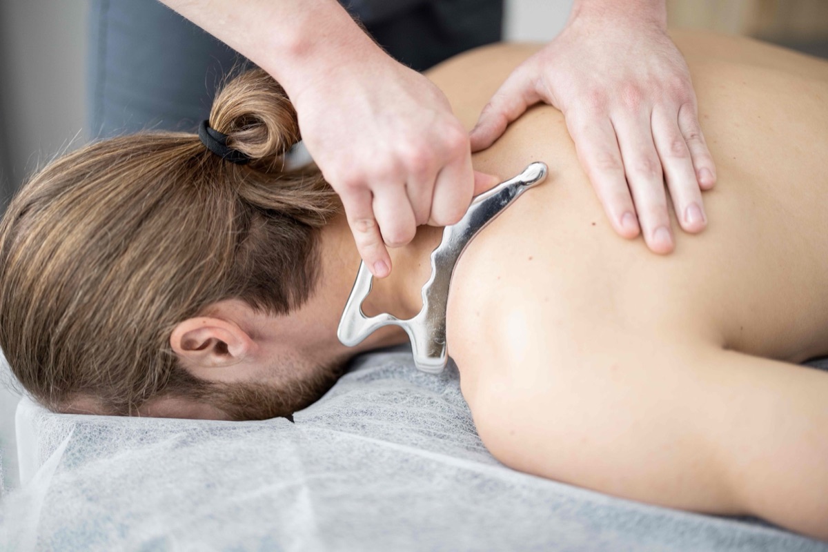 Graston Technique soft tissue treatment on a patient’s neck and shoulder